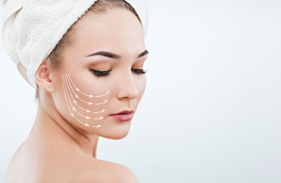 Moça com toalha cobrindo os cabelos, tem desenhado no rosto indicadores de possíveis ações da harmonização facial