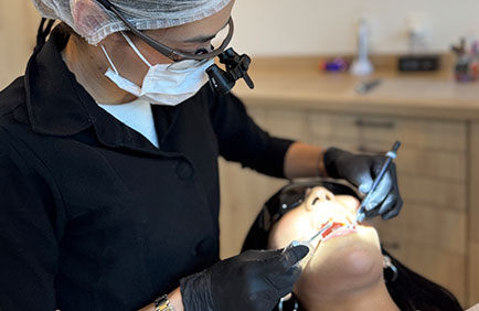 dra-debora-reis-procedimentos-avaliacao-inicial-2 Dentista realizando exame clínico com iluminação e instrumentos de avaliação bucal