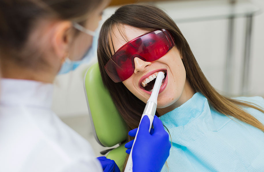 Paciente realizando clareamento dental com laser, usando óculos de proteção vermelhos