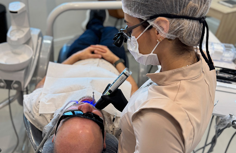 Paciente em sessão de laser odontológico com proteção ocular e ativação do feixe de luz azul