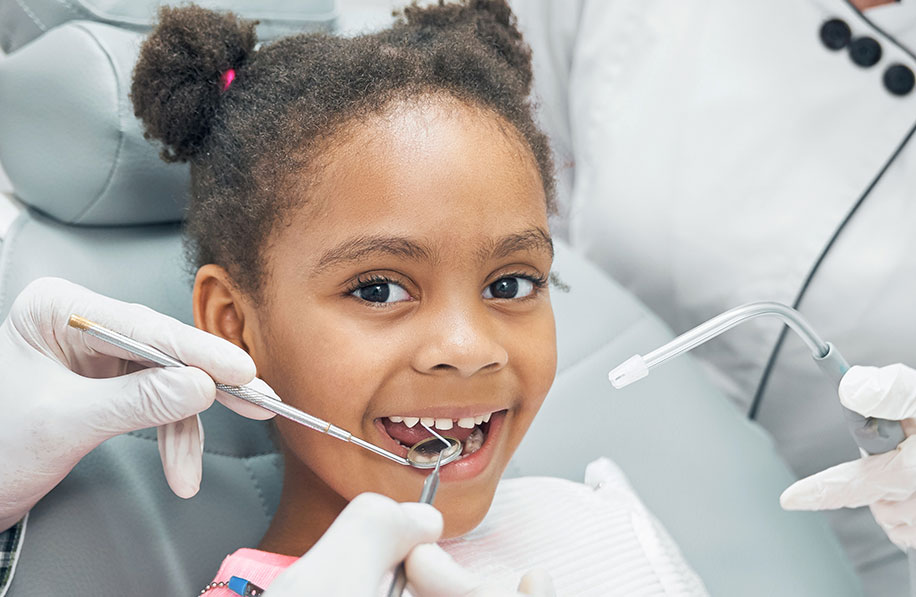 Atendimento odontológico infantil com criança sorrindo durante a avaliação no consultório