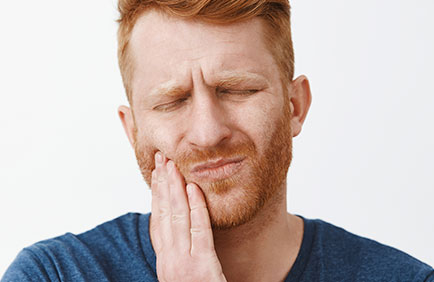 Dra Debora Reis – Periodontia Homem com dor na mandíbula devido a possível infecção gengival ou doença periodontal