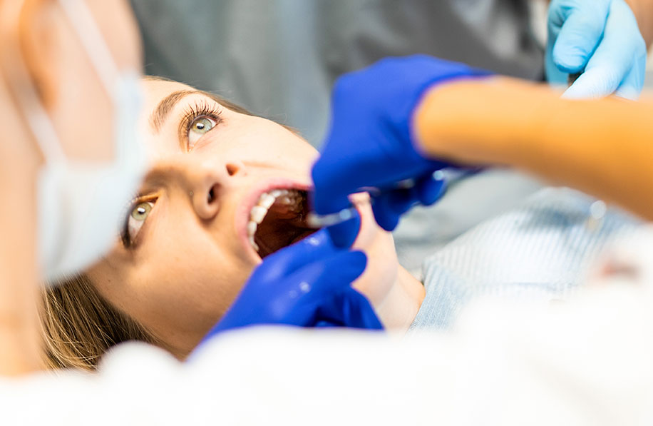 Paciente sendo preparada para procedimento de extração de siso por dentista com luvas azuis