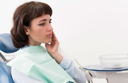 Dra Debora Reis – Endodontial | Tratamento de Canal Mulher no consultório odontológico com dor de dente, prestes a realizar avaliação endodôntica